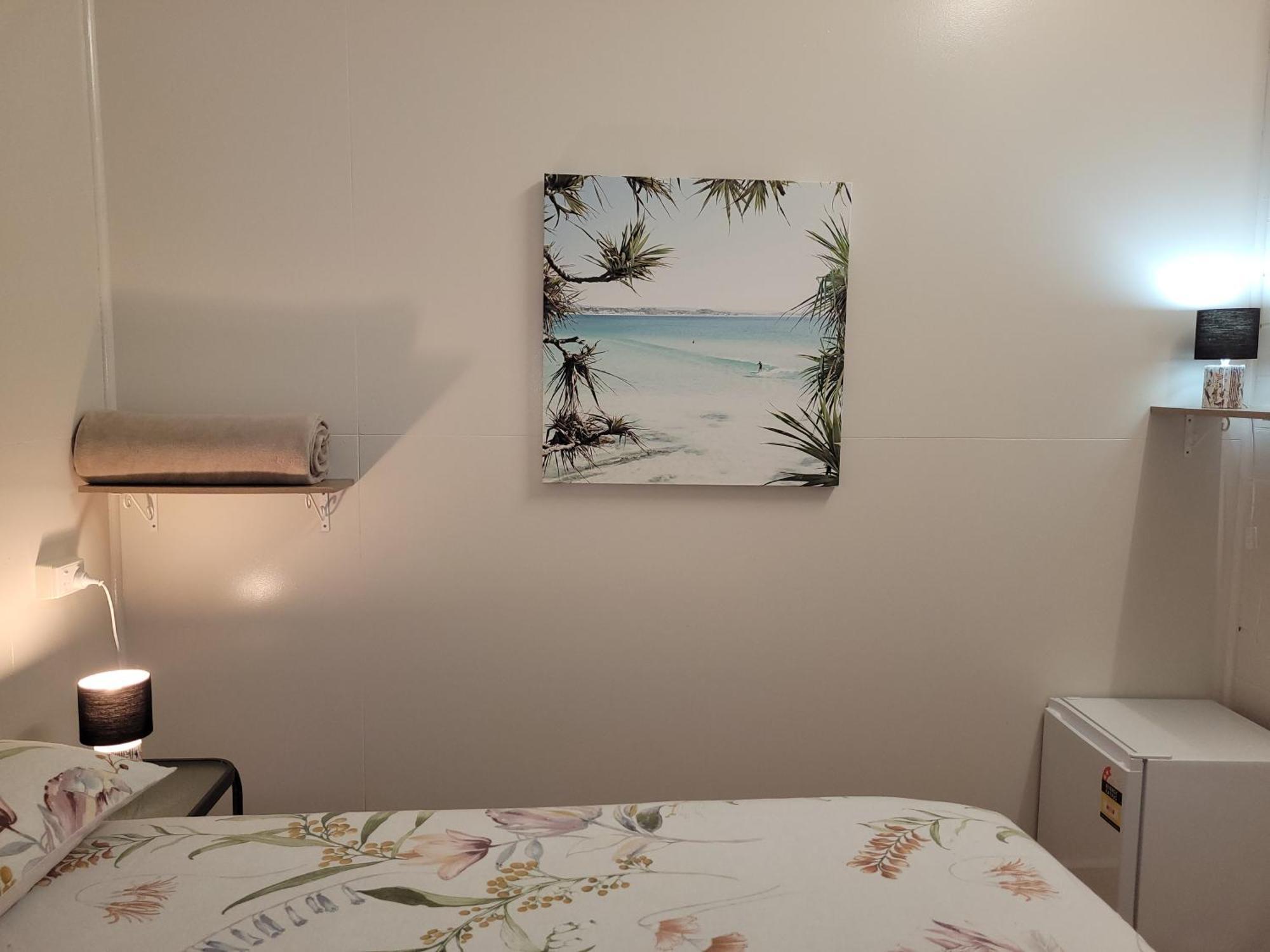 קאירנס Travellers Paradise מראה חיצוני תמונה A photograph of a bedroom with a bed, a nightstand, a lamp, a painting, and a television